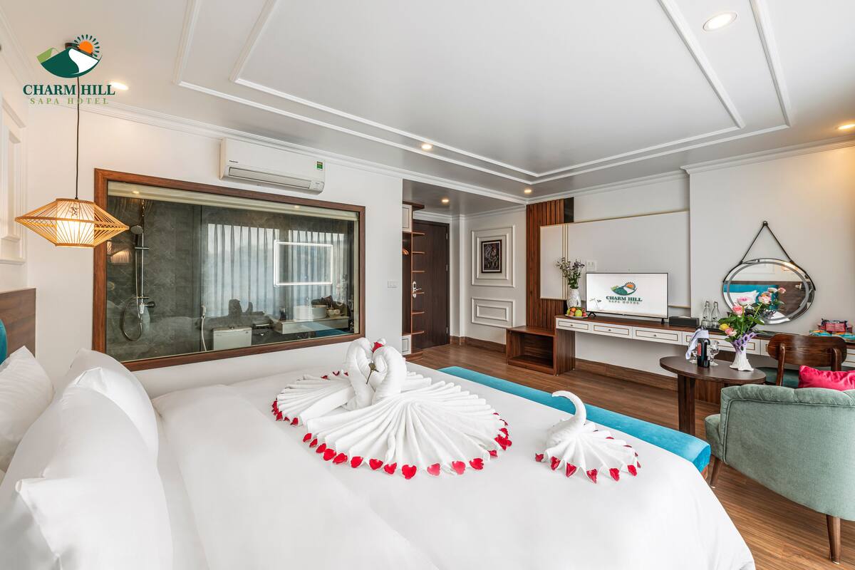 A hotel room with a large bed, a TV, a desk, and a chair.
