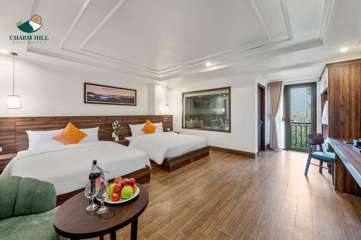 A hotel room with two beds, a dining area, and a balcony.