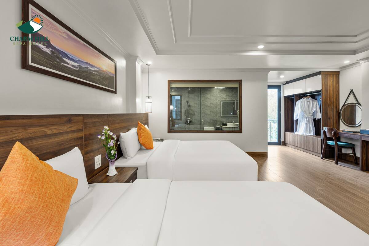 A hotel room with two beds, a large mirror, a wooden headboard, and a painting of a mountain landscape.