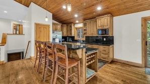 Una cocina con armarios de madera, una isla central con taburetes de bar y un microondas integrado.