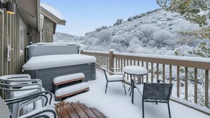 Una terraza cubierta de nieve con mobiliario exterior y un jacuzzi.