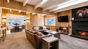 A cozy living room with a fireplace, a sofa, a coffee table, and a TV mounted on the wall. - SlopeSide • Hot Tub • Arcade • Deck w BBQ+fire pit (Big Bear Lake)