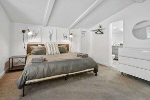 A bedroom with a bed, bedside tables, a dresser, and wall-mounted artwork.
