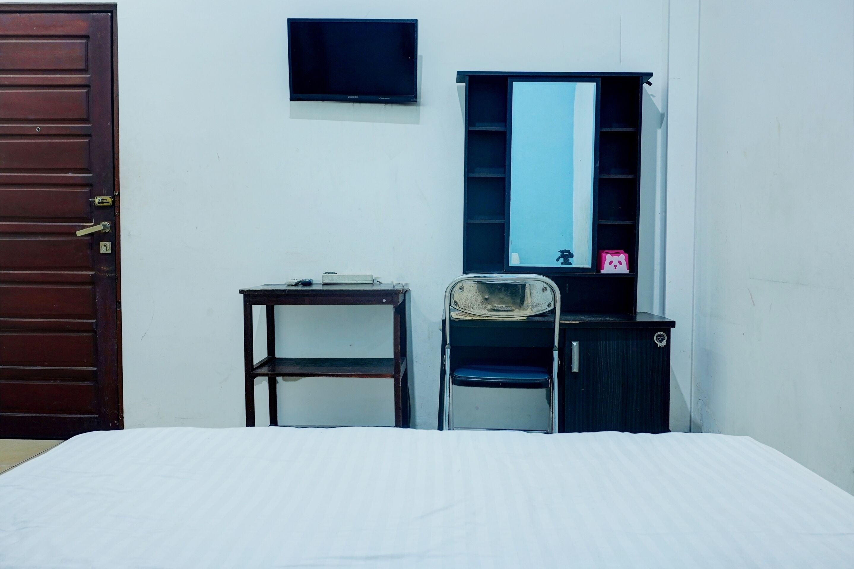 A room with a bed, a desk, a chair, a TV, and a wardrobe.