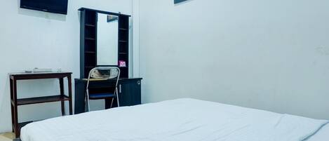 Une chambre à coucher comprenant un lit, un téléviseur fixé au mur, un bureau avec une chaise et un miroir.
