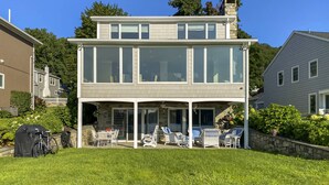 A two-story house with a covered patio area, outdoor furniture, and a stone wall.