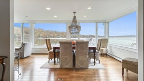A dining area with a large table, chairs, and a view of a lake.