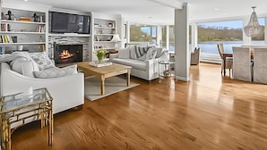 A modern living room with a fireplace, a television, and a view of a lake.