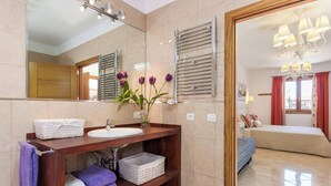 A modern bathroom with a vanity, mirror, and a bed visible through an open door. - ,,,,,kkkkkkkkkkkkkk (Petra)