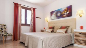 A bedroom with a large bed, a chair, a nightstand, a lamp, and a painting on the wall. - ,,,,,kkkkkkkkkkkkkk (Petra)