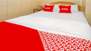 A hotel room with a bed, two red pillows with the word "OYO" on them, a white bedspread, and a red blanket with a circular pattern. - Hotel O Melati (South Tangerang)