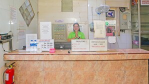 A hotel reception desk with a staff member behind it, a fire extinguisher, and various informational signs including room amenities and contact numbers. - Hotel O Melati (South Tangerang)