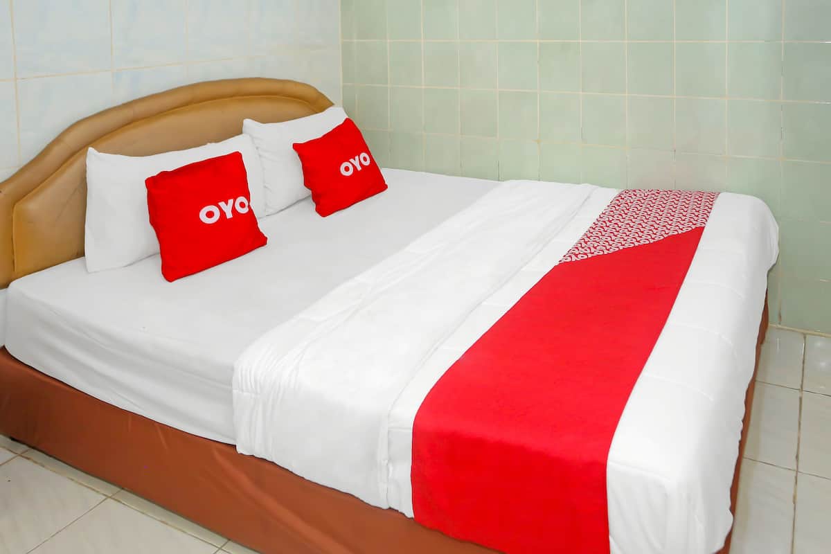 Una cama con ropa blanca y dos almohadas rojas con la palabra "oyo".