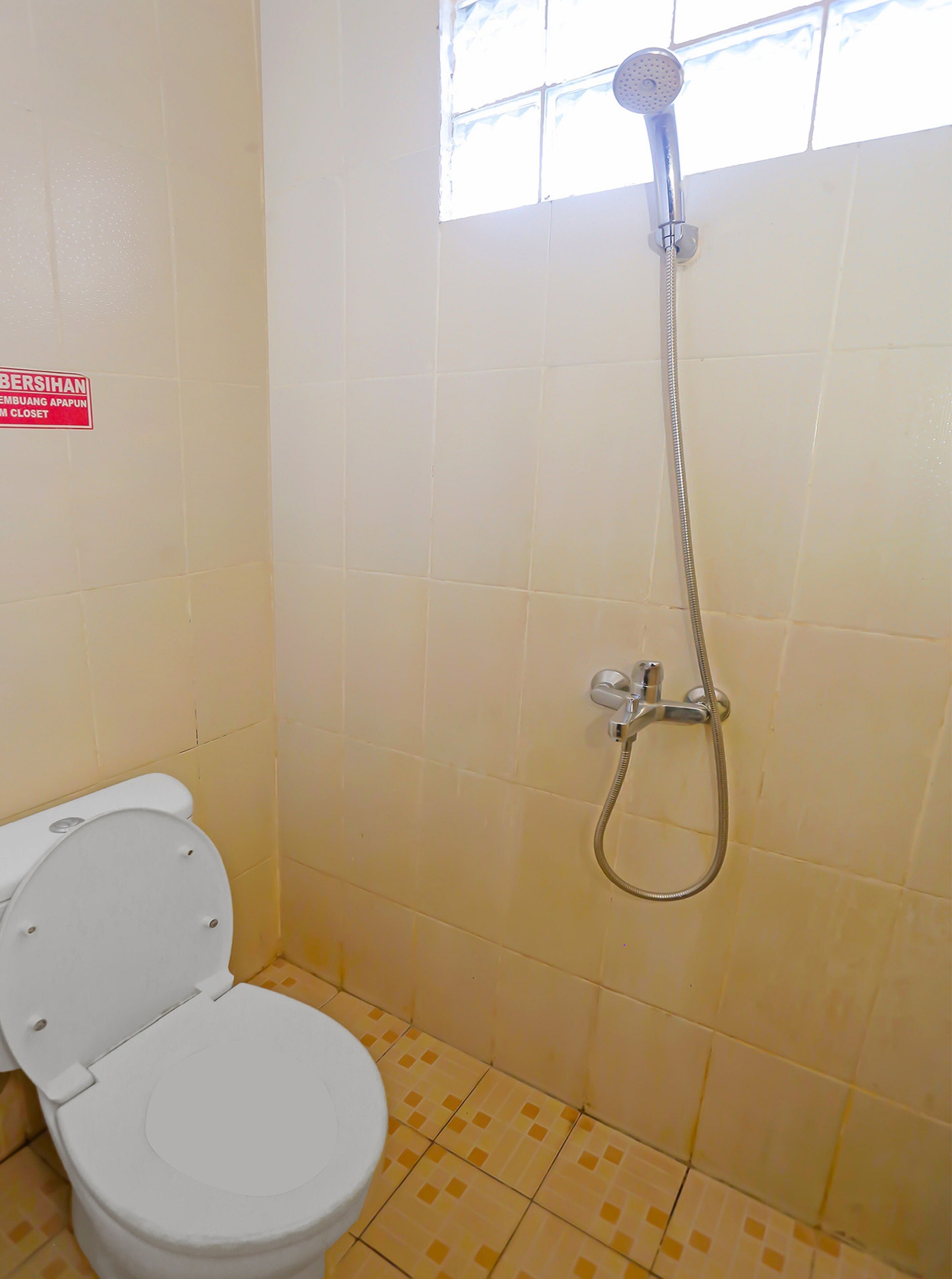 A small bathroom with a toilet, a shower, and a sign on the wall.