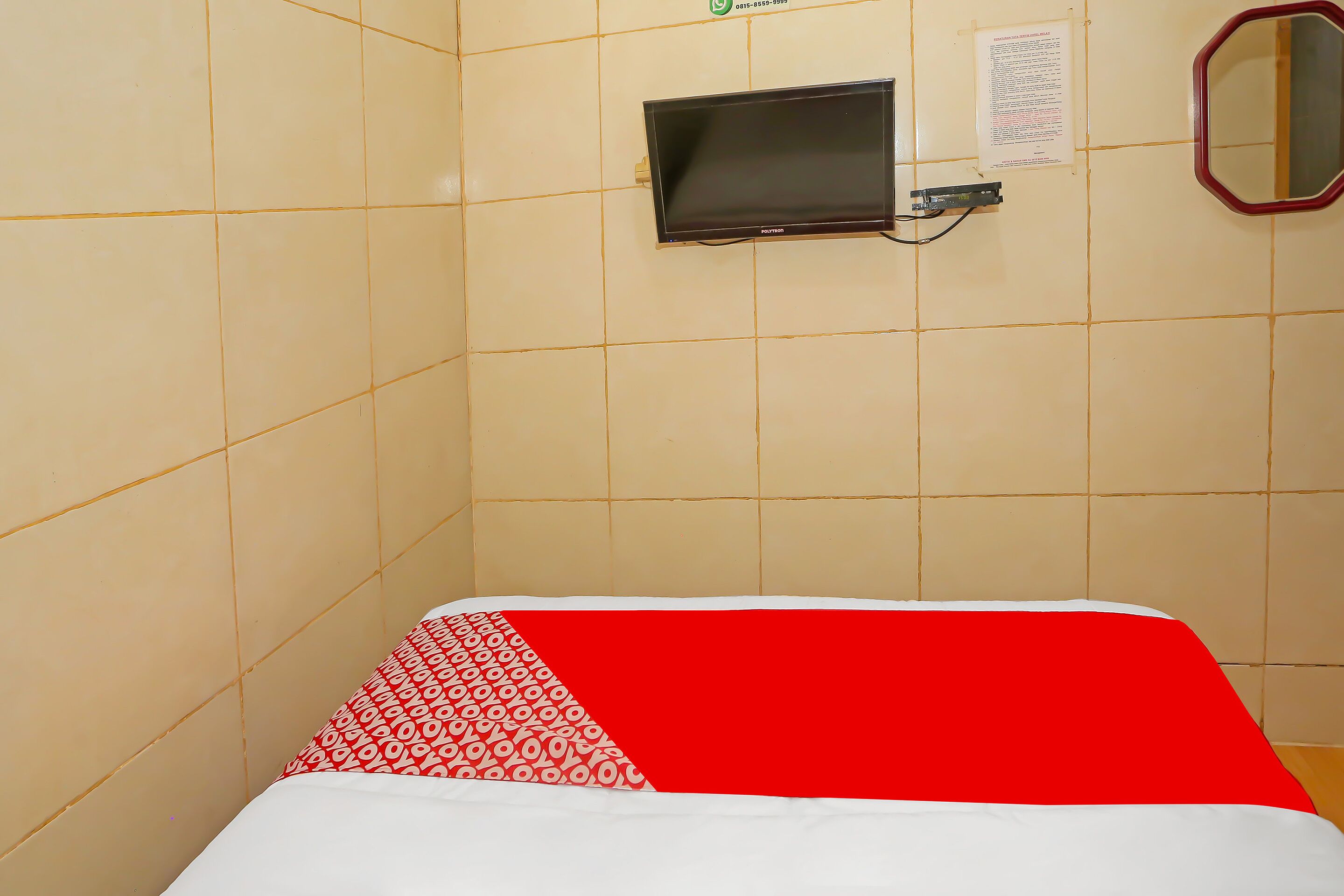 A room with a bed, a television mounted on the wall, and a mirror.