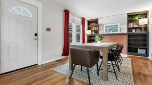 A dining area with a table, chairs, a bookshelf, and a door. - The Ohio State of Mind - OSU-Themed 5BR Home in Clintonville (Columbus)