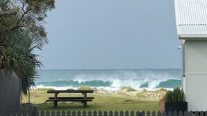Vista a la playa con un banco de madera, una valla y un edificio en primer plano.