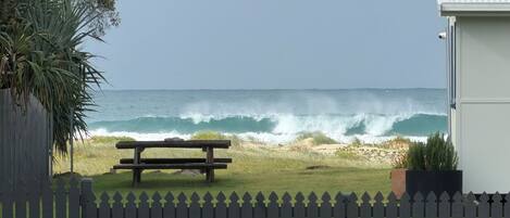 Une vue sur la plage avec un banc en bois, une clôture et un bâtiment au premier plan.