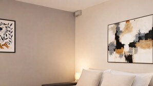 A hotel room with a bed, pillows, a blanket, and two rolled towels. - Cosy studio - Eiffel Tower & Invalides (Paris)