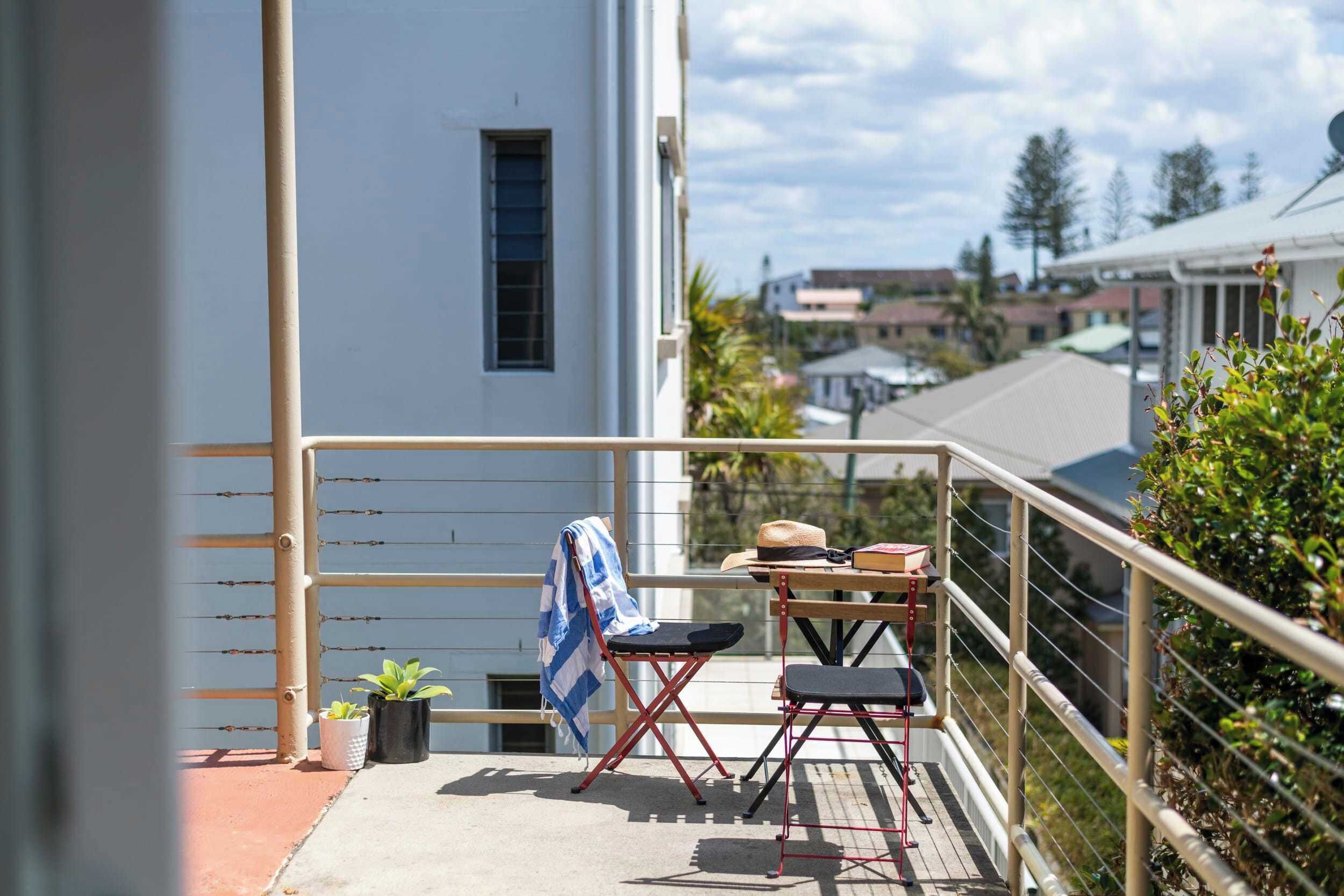 En balkon med et bord, stole og en hat på bordet.