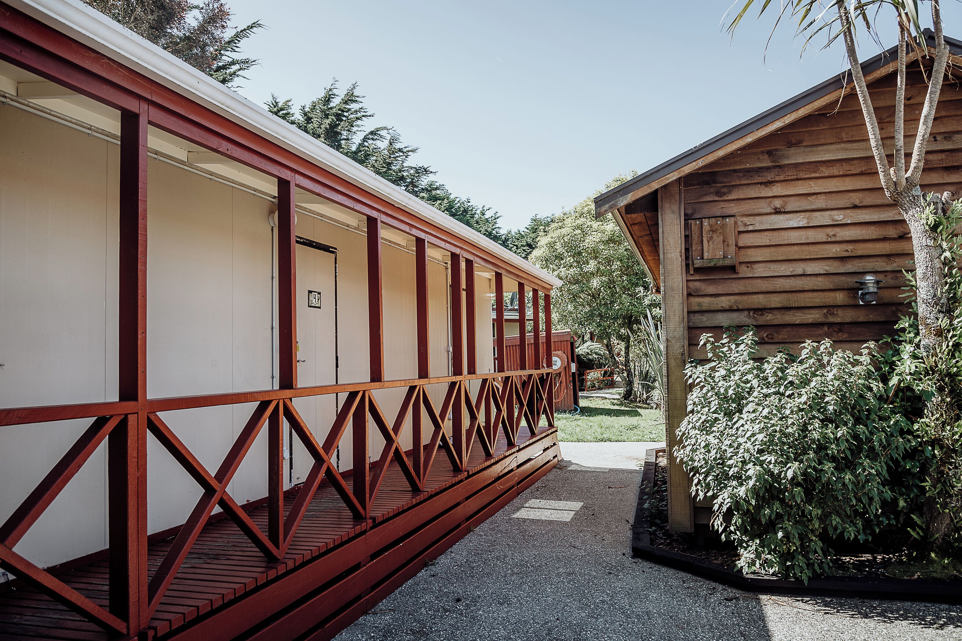 A wooden cabin with a covered porch and a small garden area.