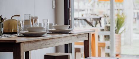 A wooden table with white plates, glasses, and a kettle.