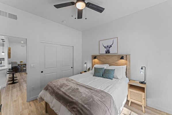 A bedroom with a bed, a ceiling fan, a nightstand, a lamp, and a framed picture on the wall. - Upscale Southwest Style Condo Tucson (Tucson)