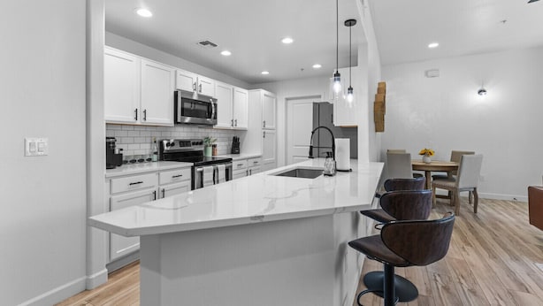 A modern kitchen with white cabinetry, a large island, and pendant lighting. - Upscale Southwest Style Condo Tucson (Tucson)