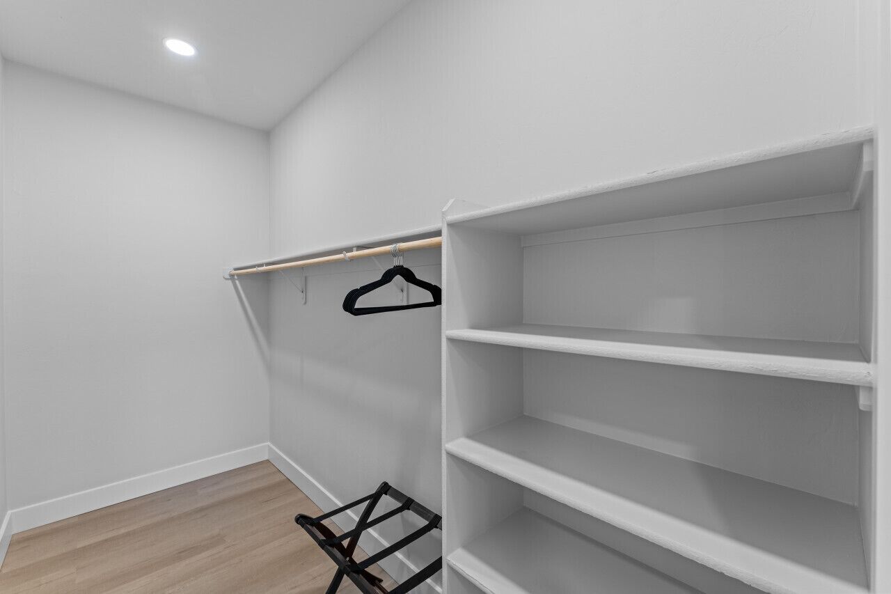 Un dressing avec des étagères blanches et une tringle pour suspendre les vêtements.
