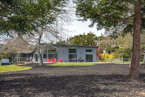 Ein modernes, zweistöckiges Gebäude mit Terrasse, Außenbestuhlung und einem eingezäunten Garten.