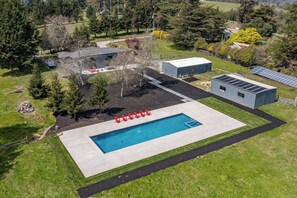 Eine Luftaufnahme eines Anwesens mit Schwimmbad, überdachtem Außenbereich und Solaranlage.