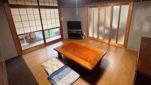 Een traditionele Japanse kamer met tatami vloeren, een lage houten tafel, verschuifbare shoji deuren en een televisie.