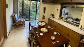 Een keuken met een eettafel gedekt voor vier personen, een groot raam en uitzicht op groen.