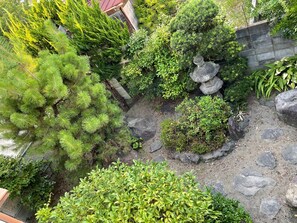 Ein Garten mit verschiedenen Pflanzen, einem Kiesweg und einer Steinskulptur.