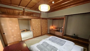 Een traditionele Japanse kamer met tatami vloerbedekking, een futon bed, een houten tafel met een kom, en schuifdeuren.