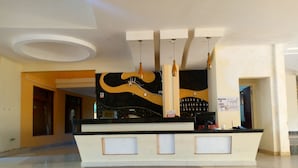 A reception area with a modern design, featuring a central counter, a decorative wall with a guitar motif, and a patterned floor. - Cool Breeze Beachfront Apartments (Mombasa)