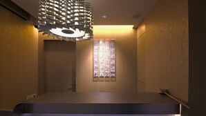 A modern interior with a wooden wall, a stained glass window, and a unique ceiling light fixture. - KABIN Gion (Kyoto)