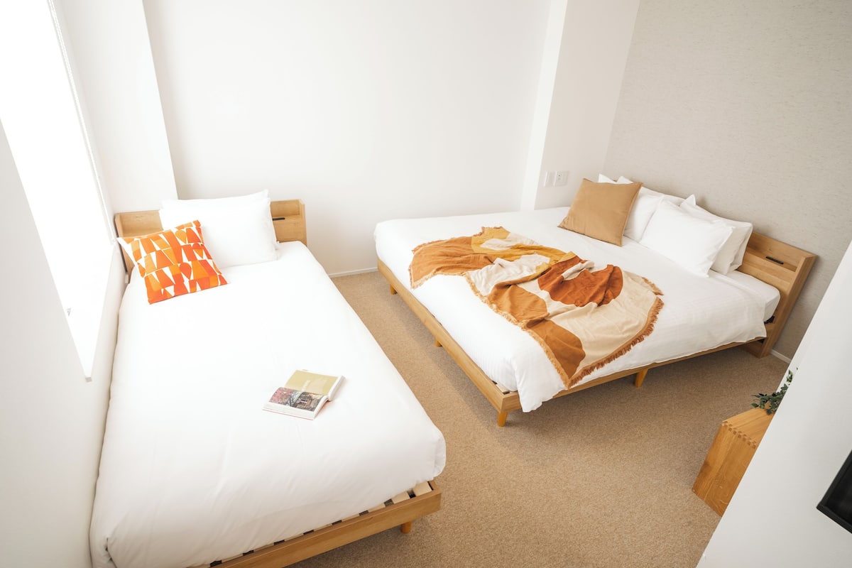 A room with two single beds, each with wooden frames and white bedding.