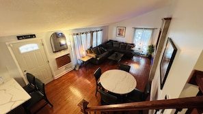 A spacious living room with a large sofa, a dining table, and a staircase leading to another level. - great home in Waukegan for navy graduate families close distance to navy base!! (Waukegan)