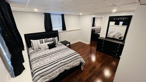 Un dormitorio con cama, cómoda, espejo y ventana con cortinas.