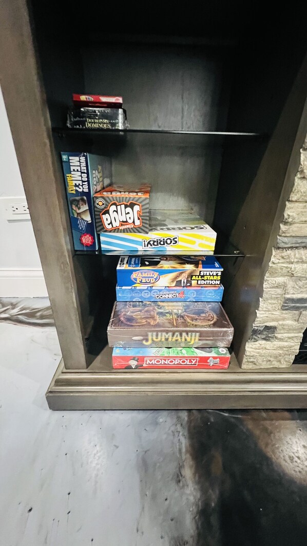 A shelf with various board games including Jumanji, Monopoly, and others.