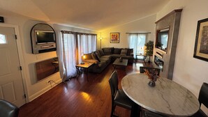 Una sala de estar acogedora con un sofá, una mesa de comedor y un televisor montado en la pared.
