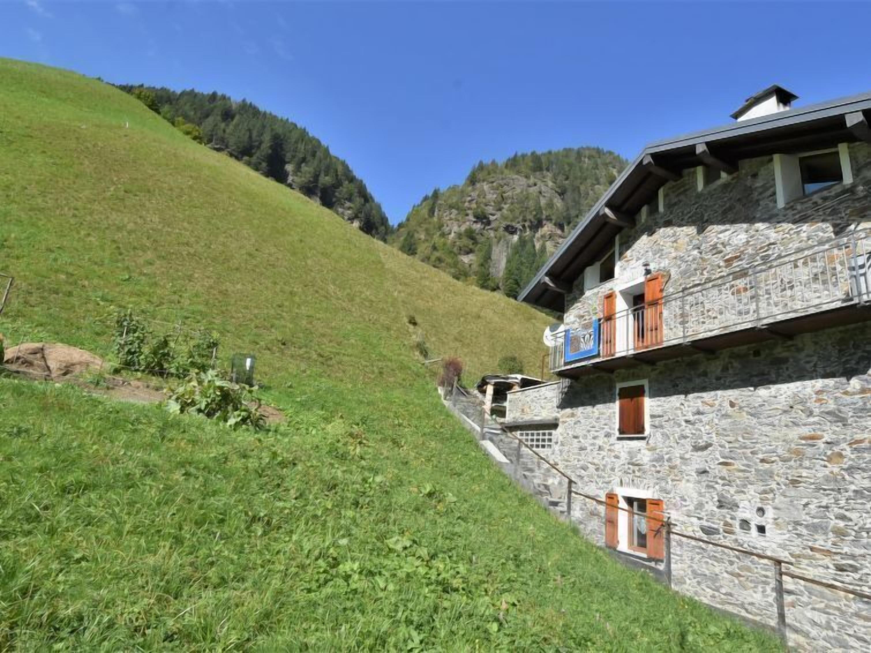 Un bâtiment en pierre doté d’un balcon, situé sur le flanc d’une colline.