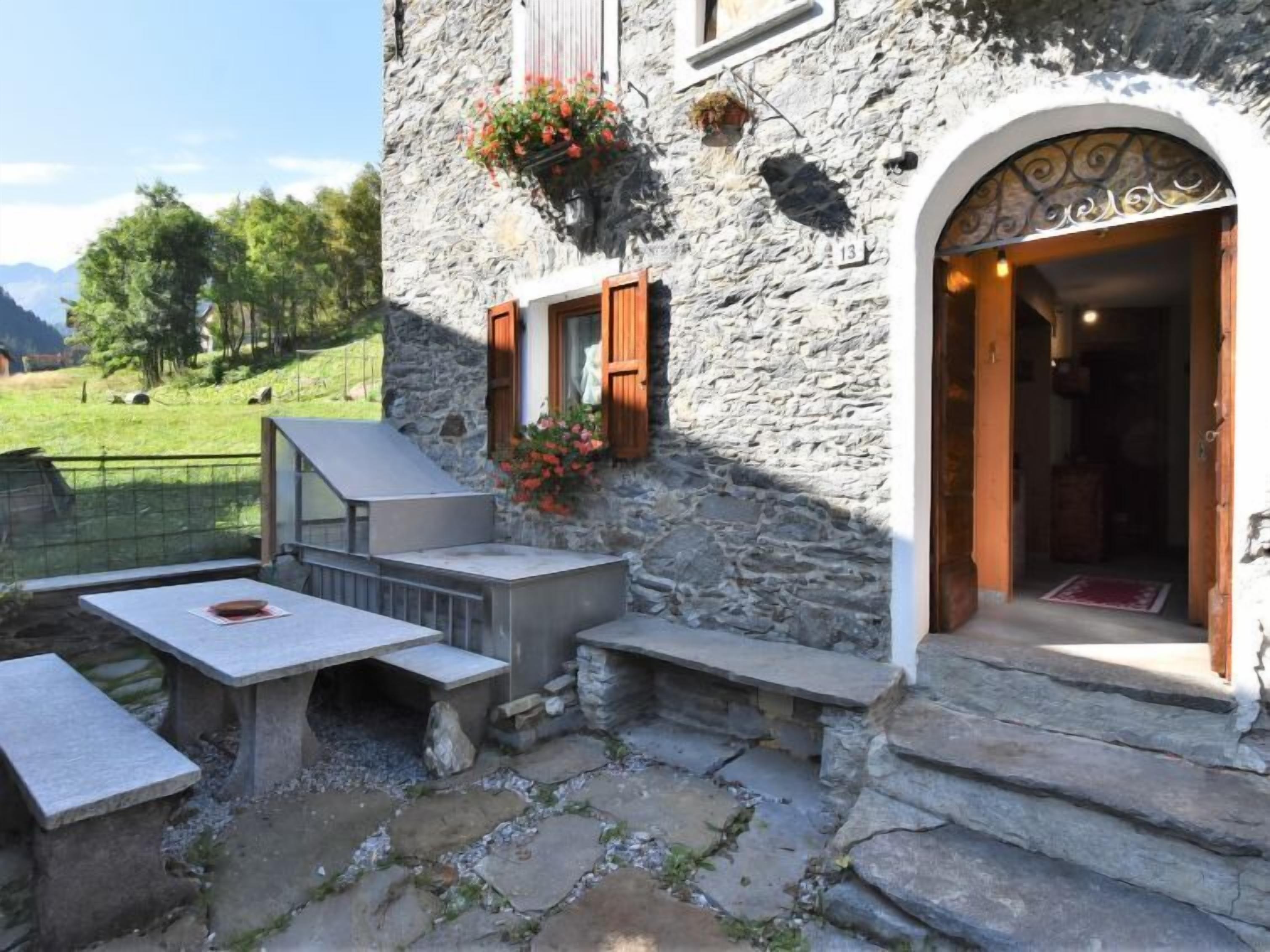 Un edificio de piedra con un patio, mobiliario exterior y una puerta de acceso.