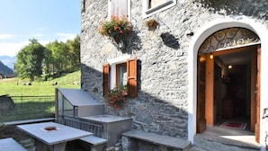 Un edificio de piedra con un patio, mobiliario exterior y una puerta de acceso.