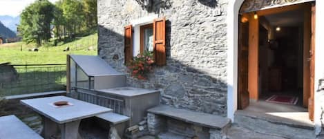 A stone building with a patio area, outdoor seating, and a door leading into the building.