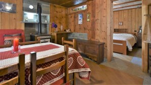 Interior acogedor de una cabaña con una mesa de comedor de madera, sillas, una cama y una pequeña kitchenette.