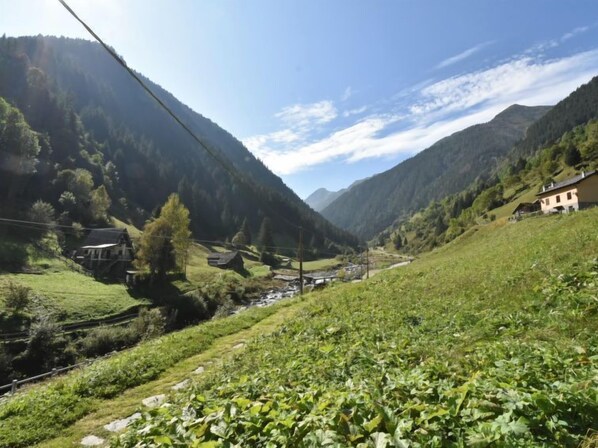A rural mountain landscape with houses, a river, and a clear sky.