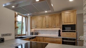 A modern kitchen with wooden cabinets, a black induction cooktop, and a built-in oven. - U Krále by Interhome (Kořenov)