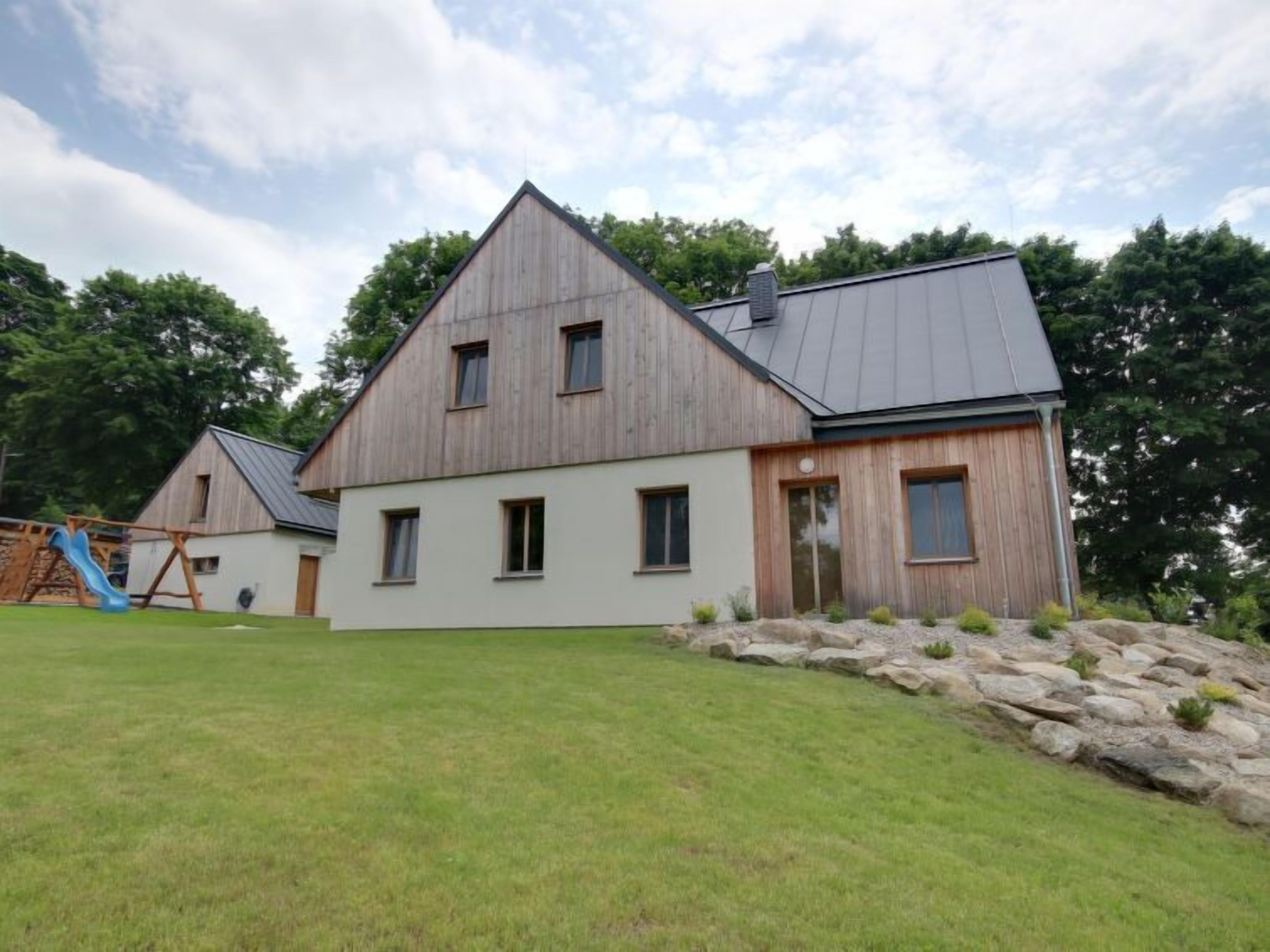 A two-story house with a sloped roof, a wooden exterior, and a front porch.